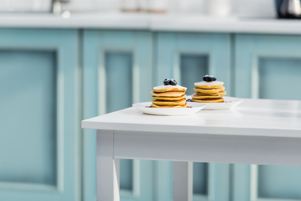 tasty pancakes with sugar powder and blueberries in plates on white table - Fotó, kép
