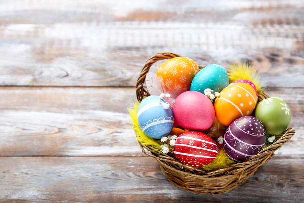 Colorful easter eggs in basket with gypsophila flowers and feath - Foto, afbeelding