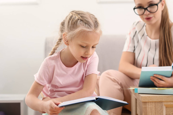 Petite fille lisant le livre au bureau d'orthophoniste
 - Photo, image