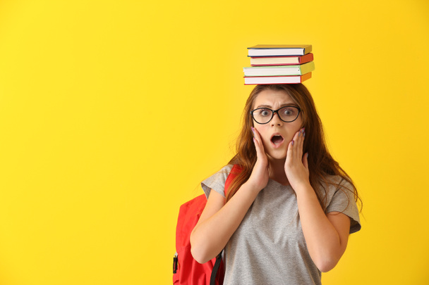 Shocked schoolgirl with books on color background - Photo, image