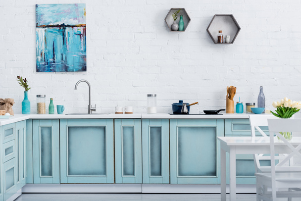 interior of modern turquoise kitchen with painting on white brick wall - Foto, imagen