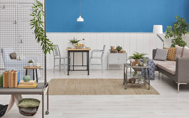 Decoração moderna da sala de jantar, mesa de madeira e cadeira preta. Fundo de parede azul e branco. Detalhe clássico da parede. Móveis cinzentos, mesa do meio, sofá e poltrona azul. Tapete de vime e lâmpada branca
. - Foto, Imagem
