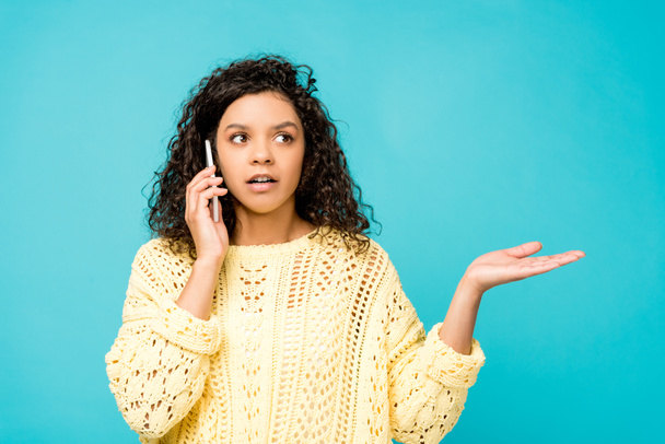 mujer afroamericana sorprendida hablando en teléfono inteligente aislado en azul
  - Foto, imagen