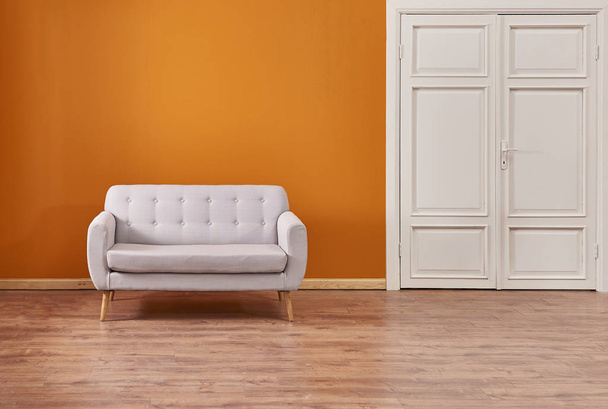 Orange wall and grey sofa, interior room
.  - Фото, изображение