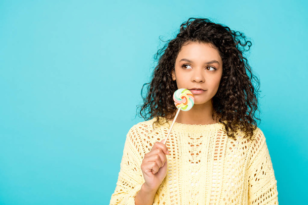attractive curly african american girl holding lollipop isolated on blue - Photo, Image