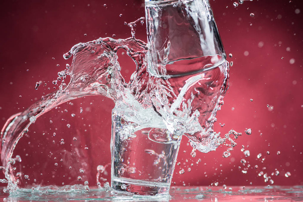 falling small glasses and spilling water on a red background - Foto, Imagem
