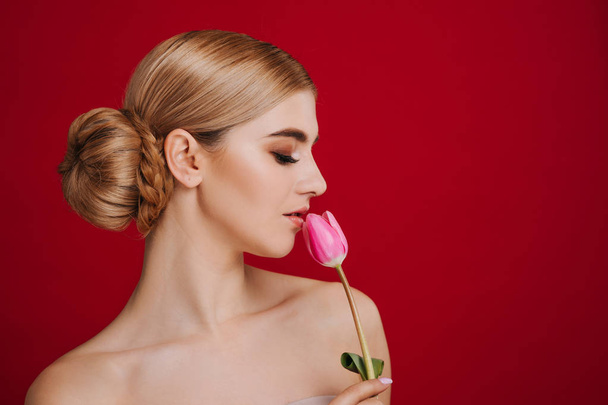 Portret van mooie jonge blonde vrouw met glamour make-up. Meisje bedrijf roze tulp. Studio schoot. - Foto, afbeelding