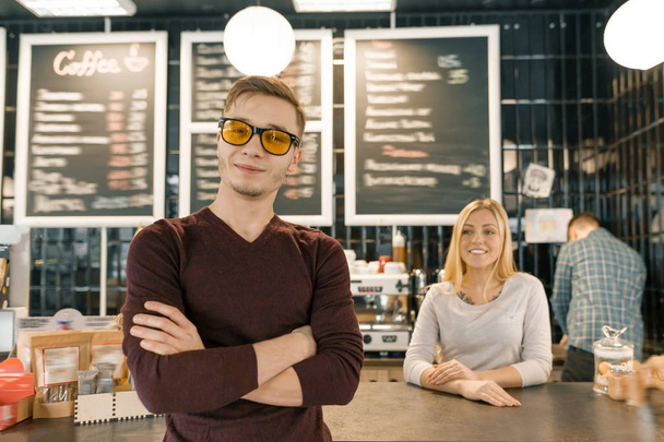 Young team of three cafe workers, people posing and smiling at coffee bar near bar counter. Teamwork, staff, small business, people concept - Valokuva, kuva