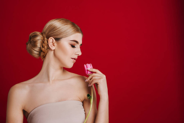 Portret pięknej młodej kobiety blondynka z makijaż glamour. Dziewczynka gospodarstwa różowe tulip. Strzał studio. - Zdjęcie, obraz