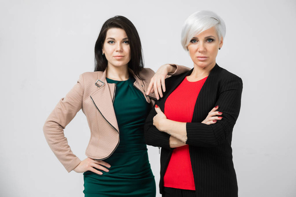 Porträt von zwei jungen Geschäftsfrauen in Kostümen isoliert auf dem Hintergrund - Foto, Bild