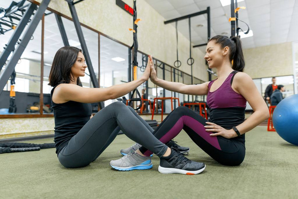 Dos jóvenes mujeres sanas haciendo ejercicio juntas en el gimnasio. Fitness, deporte, entrenamiento, personas, concepto de estilo de vida saludable
. - Foto, Imagen