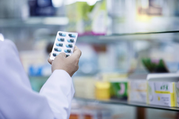 Main avec capsule bleue en pharmacie, Pharmacie
 - Photo, image