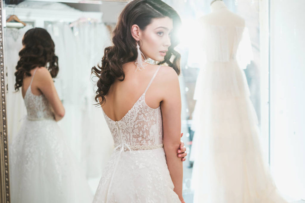 Beautifu bride choosing wedding dress in a wedding salon - Фото, изображение