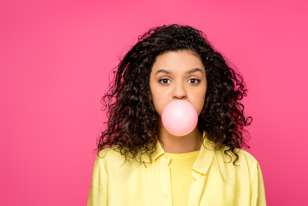 attractive curly african american woman blowing bubble gum isolated on crimson  - Photo, Image