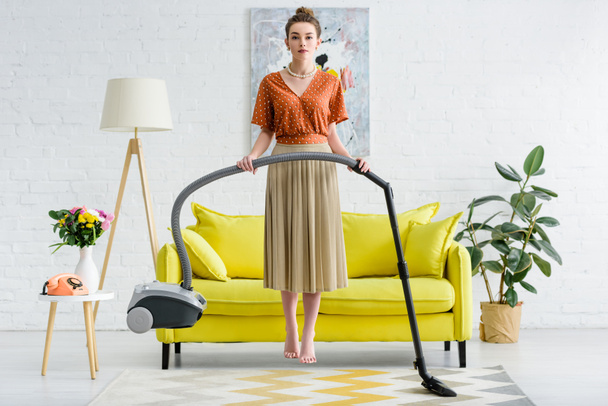 elegant barefoot young woman levitating in air and holding vacuum cleaner - Photo, Image