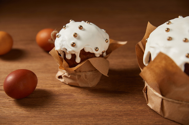 huevos de pollo pintados y pasteles de Pascua decorados con aspersiones y glaseado en la superficie de madera
 - Foto, Imagen