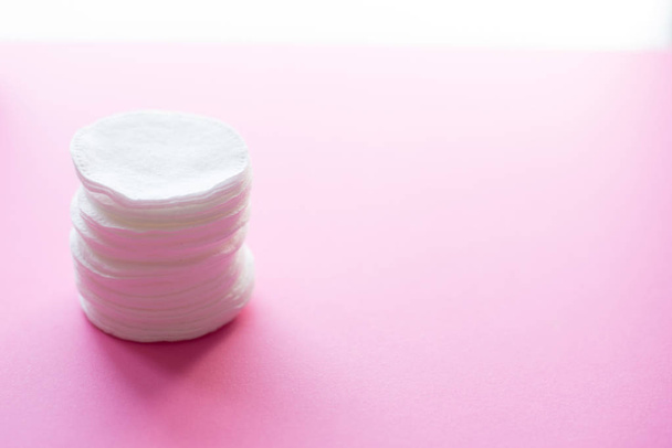 Clean white cotton stack of disk for beauty face hygiene with selective focus on pink neutral background. Cosmetic softness pure sponge for makeup remover. Sterile cleanliness facial sponges - Photo, Image