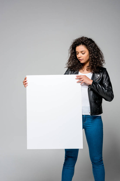 attractive curly african american woman holding blank placard while standing on grey - Photo, Image