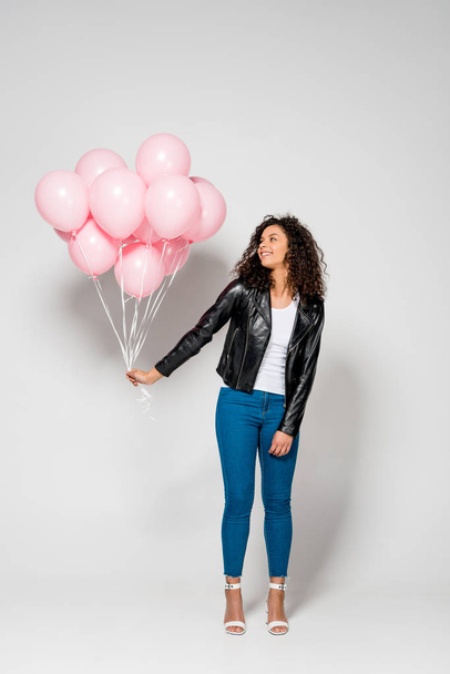 happy african american young woman holding pink air balloons on grey - Fotó, kép