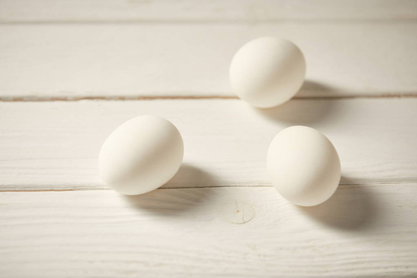 selectieve aandacht van ongekookt kip eieren op witte houten planken - Foto, afbeelding