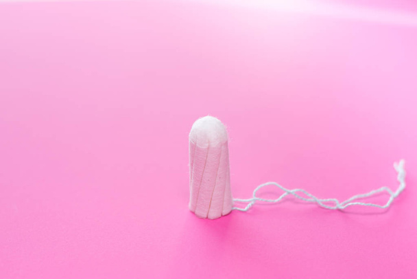 Tampón médico femenino en un fondo rosado. Tampón blanco higiénico para mujeres. Cotton swab. Sólo una cucharada en un fondo rosa. copiar espacio. - Foto, imagen