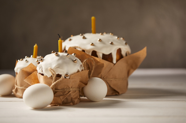 traditional easter cakes with candles and chicken eggs on white surface - 写真・画像