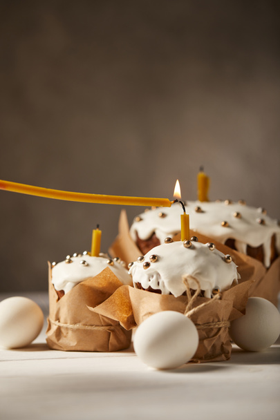 смачні великодні торти зі свічками та курячими яйцями на білому столі
 - Фото, зображення