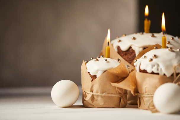 traditional easter cakes with burning candles and chicken eggs on white table with copy space - Foto, Imagem