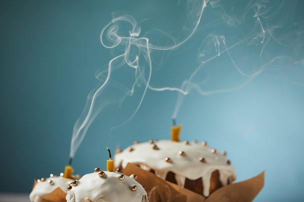 selective focus of decorated easter cakes with candles and smoke on turquoise - Photo, Image