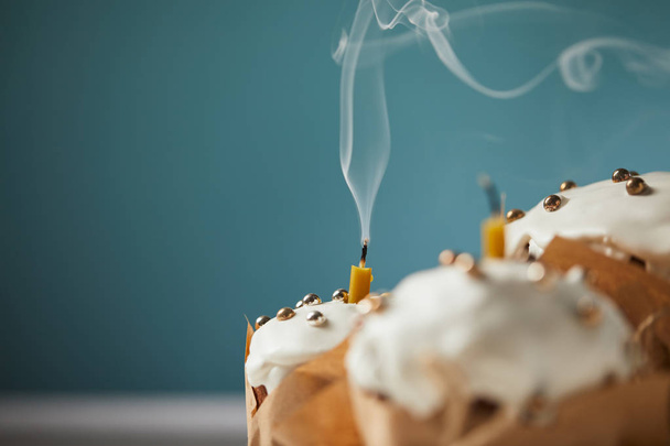 Selektivní fokus zdobené velikonoční dorty se svíčkami a kouř na tyrkysové - Fotografie, Obrázek