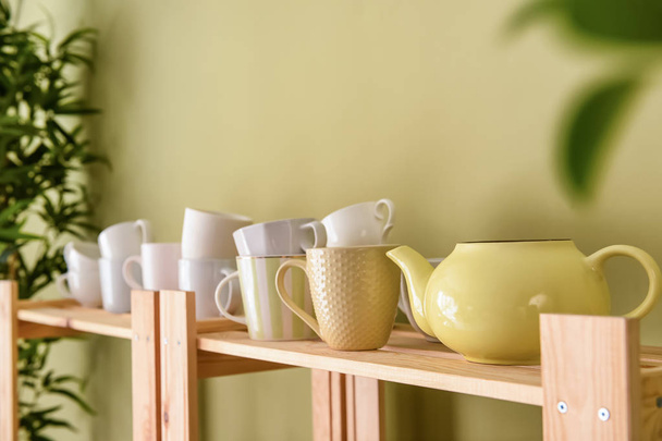 Set of clean dishes on wooden shelf near color wall - Photo, Image