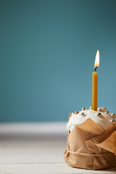 foco seletivo de bolo de Páscoa decorado com polvilhas e vela acesa em turquesa com espaço de cópia
 - Foto, Imagem
