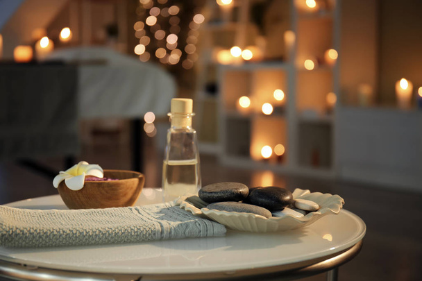 Massagesteine, Handtuch und ätherisches Öl auf dem Tisch im Wellnessbereich - Foto, Bild