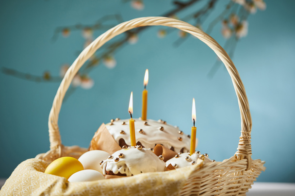 selective focus of easter cakes with chicken eggs and napkin in wicker basket on turquoise - Photo, Image