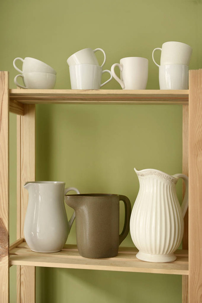 Set of clean dishes on wooden shelves near color wall - Photo, Image