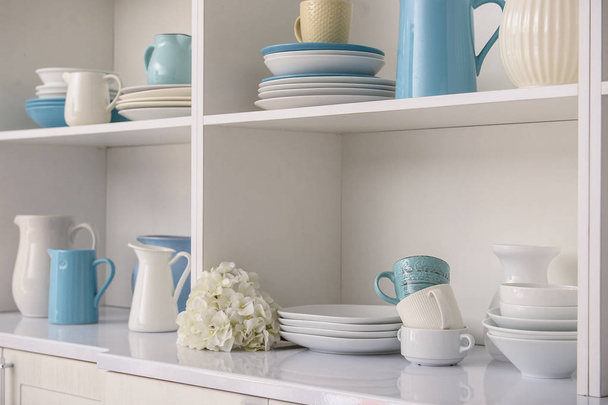 Set of clean dishes on white shelves in kitchen - Photo, Image