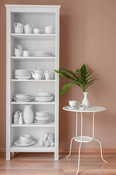 Set of clean dishes on shelves near color wall - Photo, Image