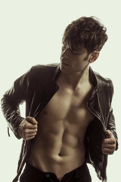 Strong stripped muscle male model in casual look in black leather jacket on white isolated font background - Foto, Imagem
