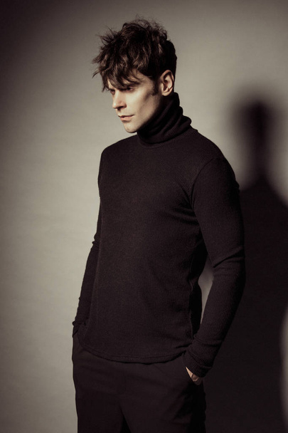 stark entblößte muskulöse männliche Modell in lässigem Look in schwarzer Lederjacke auf schwarzem, isolierten Schrifthintergrund - Foto, Bild