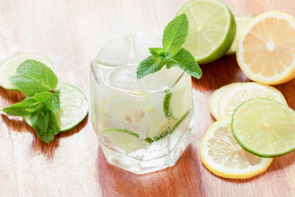A glass of cold water with lemon and lime, ice cubes and mint leaves - Fotoğraf, Görsel