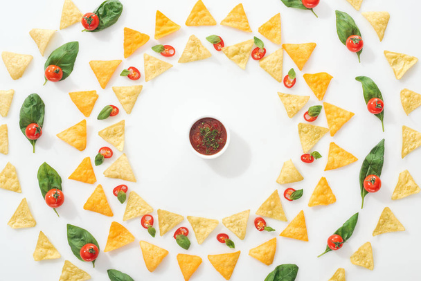a finom nachos, mártással és szeletelt chili paprika bazsalikommal és cseresznyeparadicsommal felülnézete  - Fotó, kép