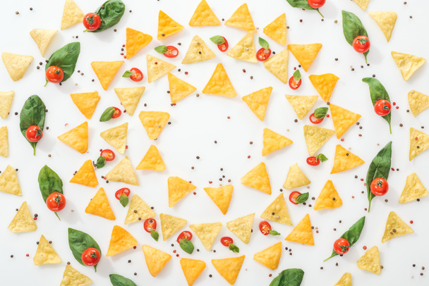 posa piatta con gustosi nachos, spezie e peperoncini tagliati a fette con basilico e pomodorini interi
 - Foto, immagini