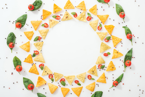 flat lay with tasty nachos, spices and sliced chili peppers with basil and ripe cherry tomatoes - Photo, Image