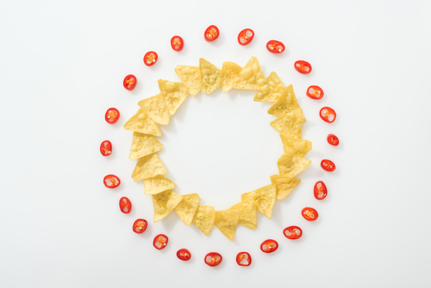 top view of sliced chili peppers and tasty nachos on white background with copy space  - Fotó, kép