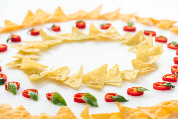 szelektíven összpontosít ízletes nachos és chili paprika bazsalikommal fehér alapon  - Fotó, kép