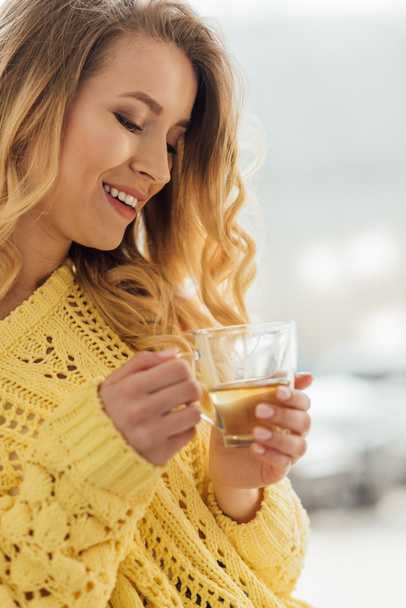 selective focus of beautiful smiling young woman holding cup of tea  - Photo, image
