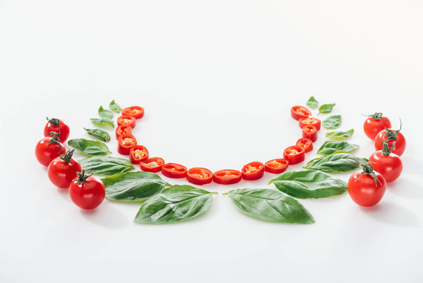 flat lay with cut chili peppers, basil leaves and ripe cherry tomatoes on white background  - Photo, Image