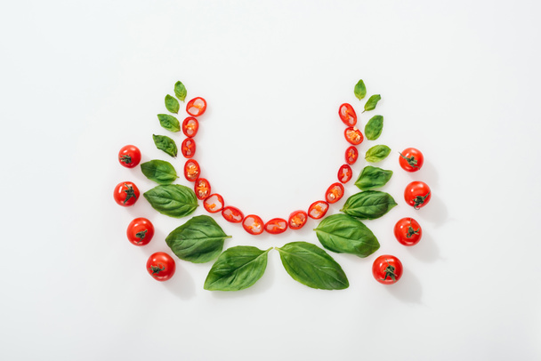top view of cut chili peppers, basil leaves and ripe cherry tomatoes on white background  - Фото, зображення