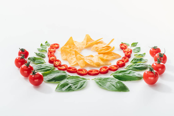 flat lay with nachos, cut chili peppers, basil leaves and ripe cherry tomatoes  - Photo, Image