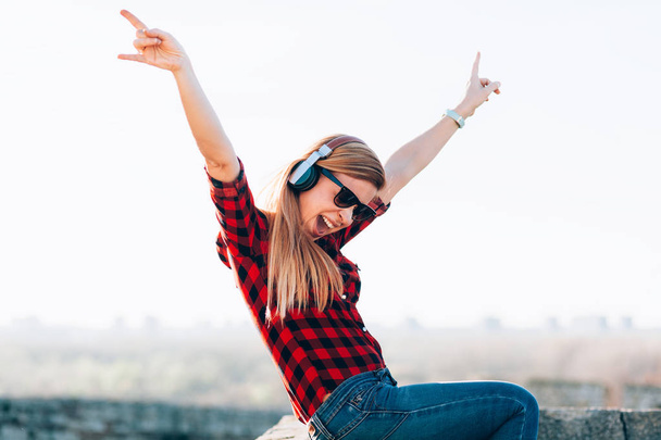 Young woman listening to the music on headphones outdoors - Foto, Bild